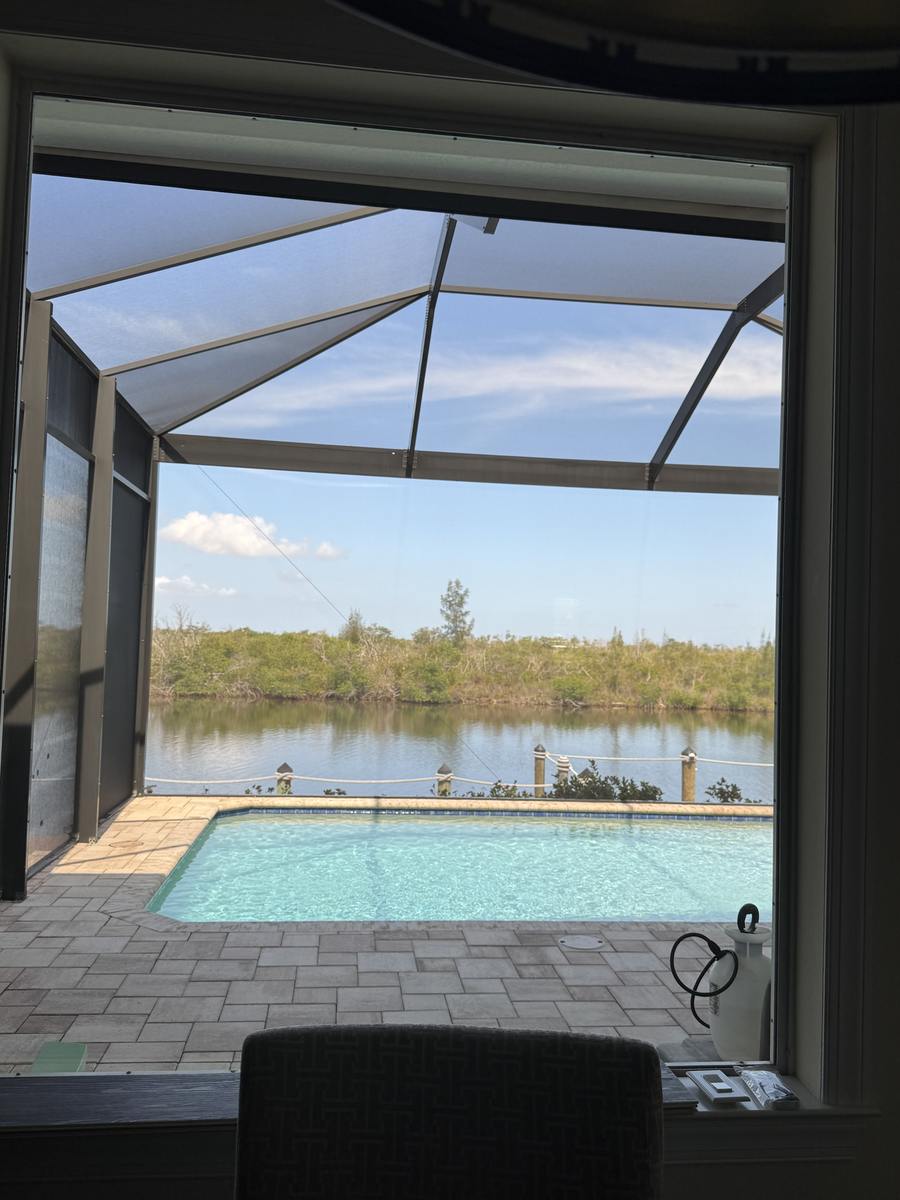 Clean window looking out over a screened pool cage and canal in Cape Coral, Florida