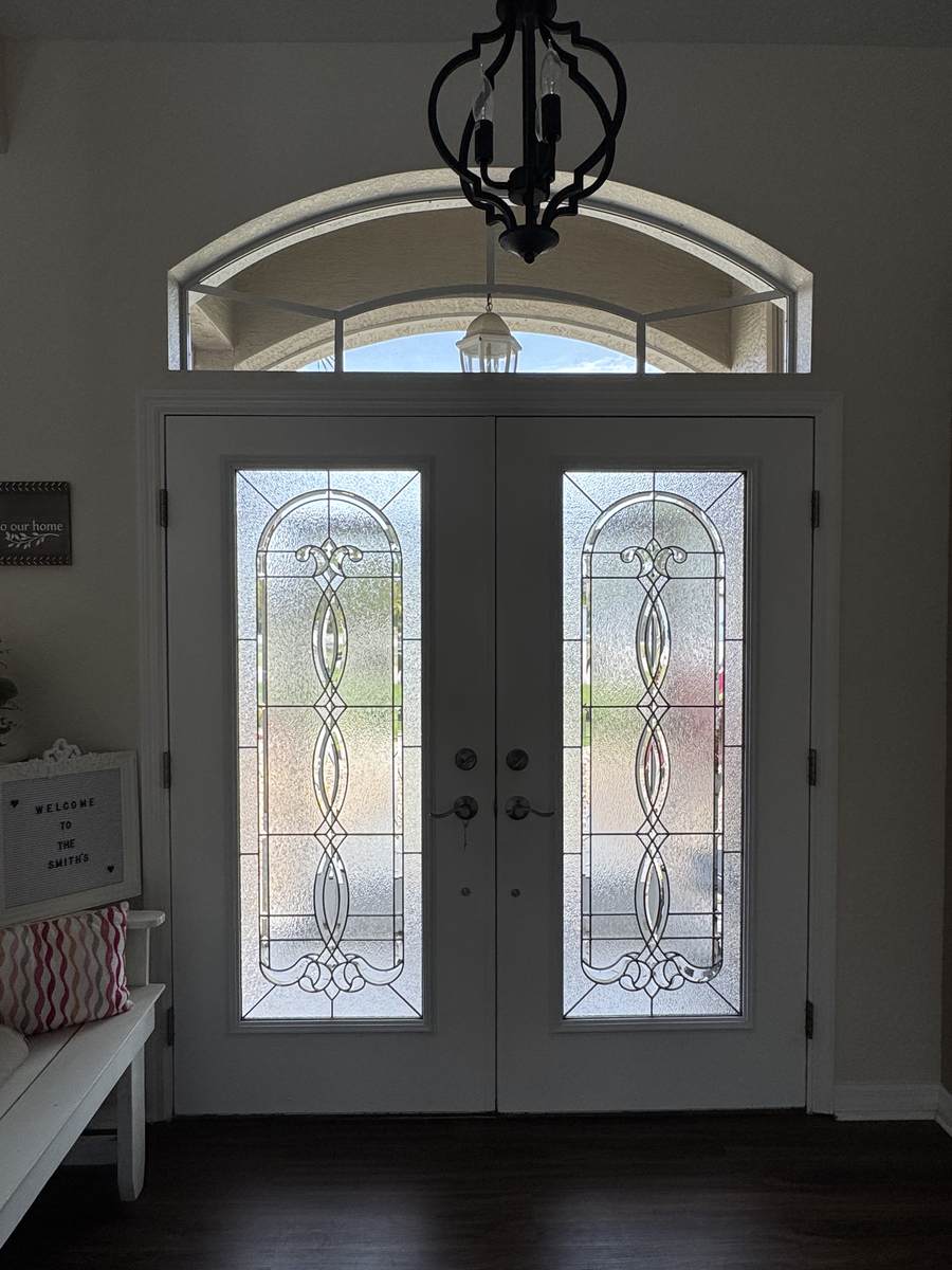 Freshly cleaned decorative glass double entry doors and arched transom window